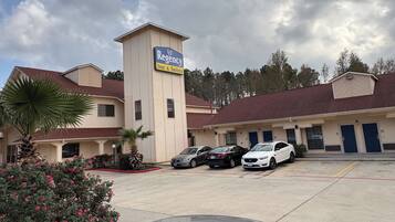 A Regency Inn & Suites with a parking lot, several cars, and a palm tree.