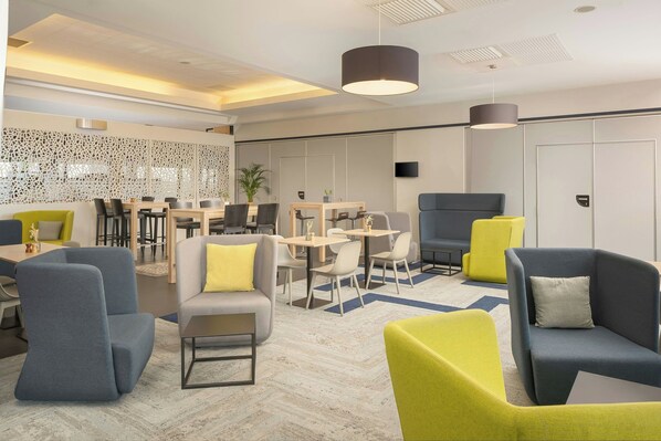 A modern lounge area with seating, tables, and a decorative wall.