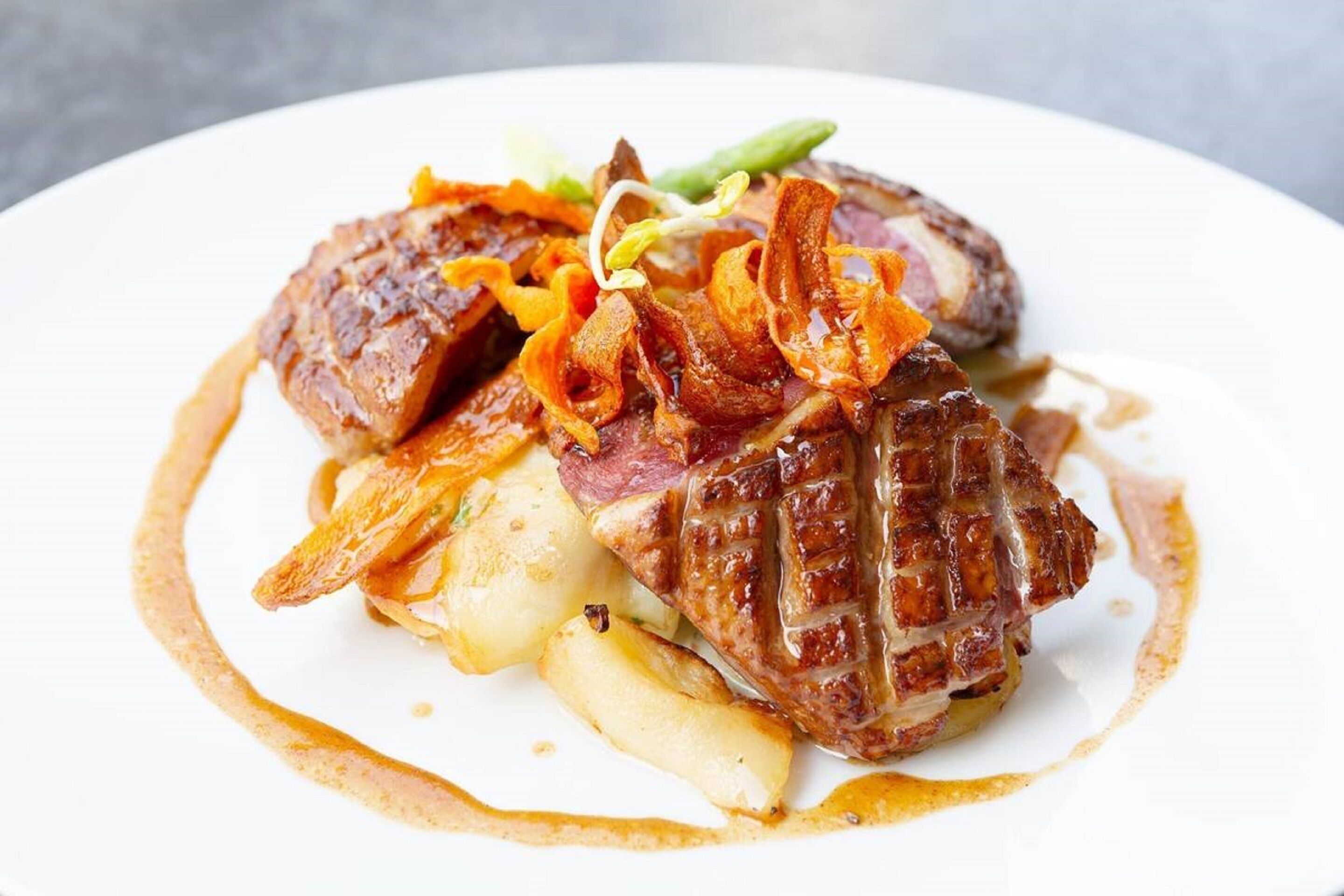 A plate of food with steak, potatoes, and caramelized onions.