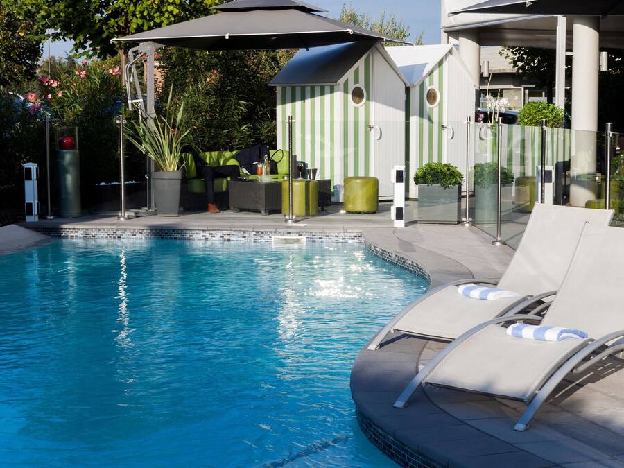 A swimming pool with lounge chairs and a covered seating area.