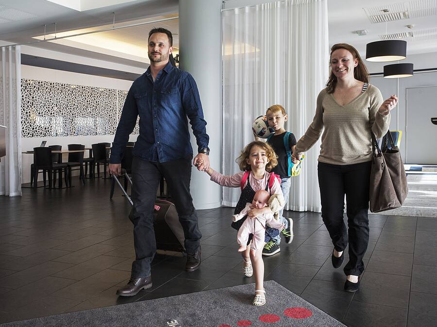 Een moderne hotellobby met een zithoek, decoratieve muur en een grote pijler.