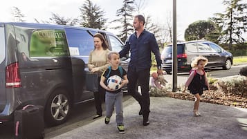 Een gezin loopt naar een Courtyard Marriott hotel, met een auto in de buurt.