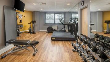 Une salle de sport équipée de tapis de course, d’un banc et d’appareils de musculation.