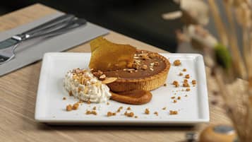 Un postre sobre un plato blanco, con una servilleta y cubiertos al fondo.