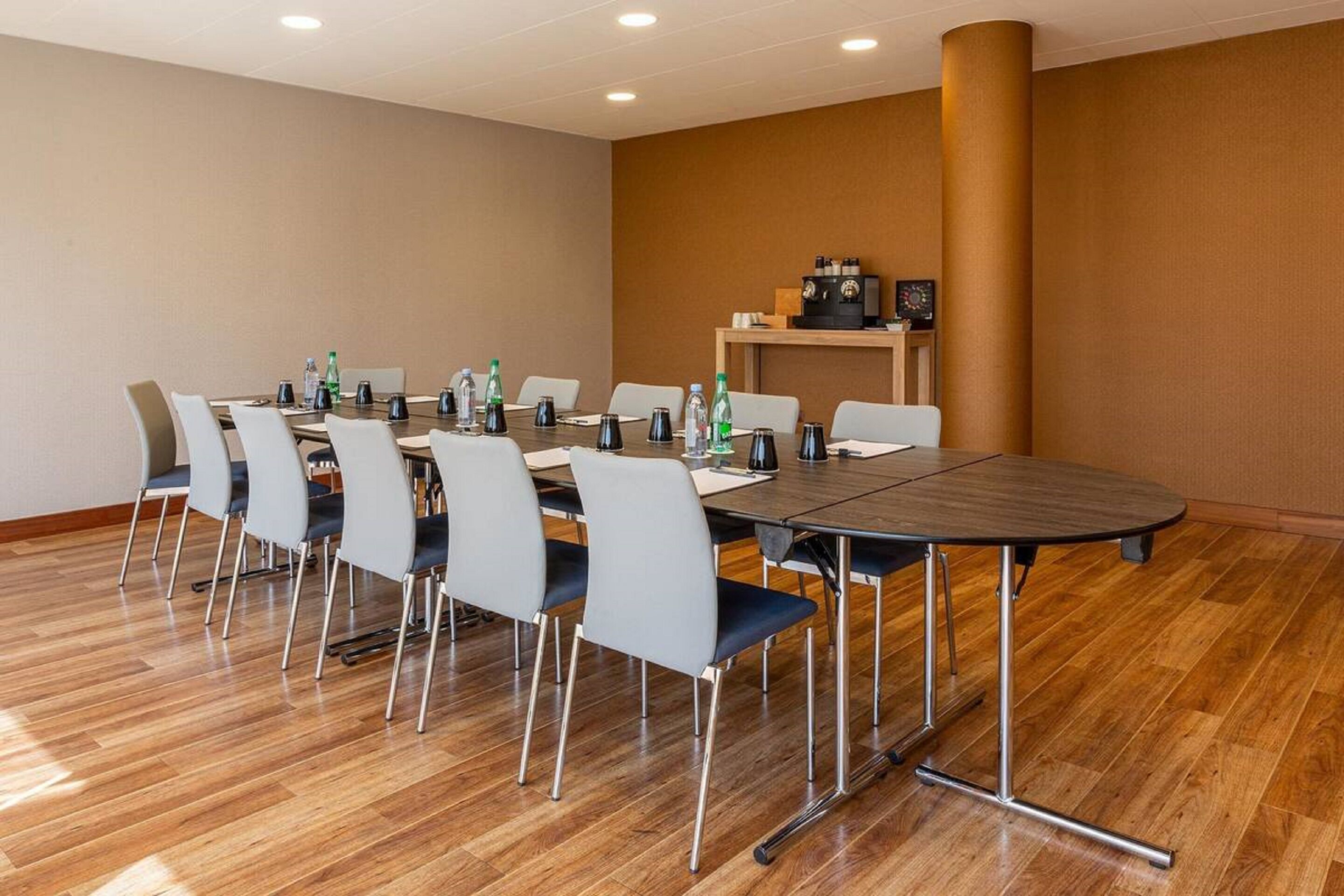 A conference room with a long table, chairs, and a coffee station.