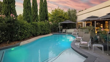 Una piscina al aire libre de temporada, sombrillas
