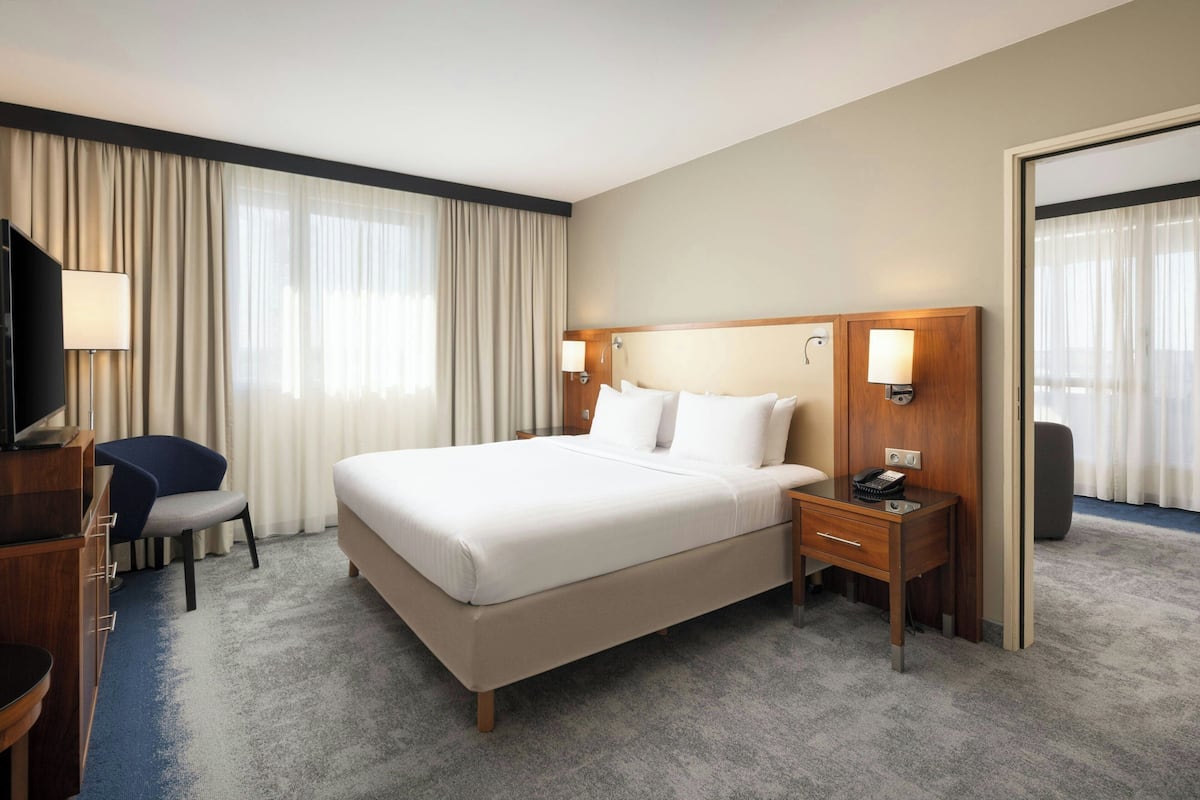 Une chambre d’hôtel avec un grand lit, un bureau avec une lampe, une chaise et un téléviseur.