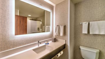 A modern bathroom with a large mirror, white sink, and toilet.