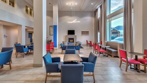 A spacious hotel lobby with a central seating area, a fireplace, and large windows offering a view of the outside. - Holiday Inn Express Hotel & Suites Minden by IHG (Minden)