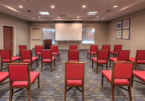 A conference room with rows of red chairs, a projector screen, and a patterned carpet. - Holiday Inn Express Hotel & Suites Minden by IHG (Minden)