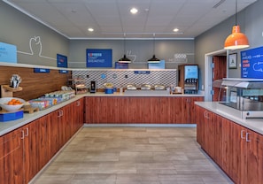 A modern breakfast area with a central counter, various food stations, and informational signs. - Holiday Inn Express Hotel & Suites Minden by IHG (Minden)