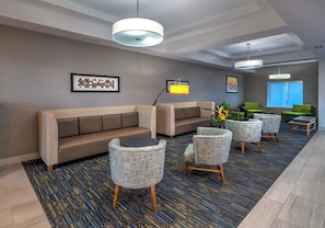 A modern lobby with a sectional sofa, round chairs, a coffee table, and artwork on the walls.