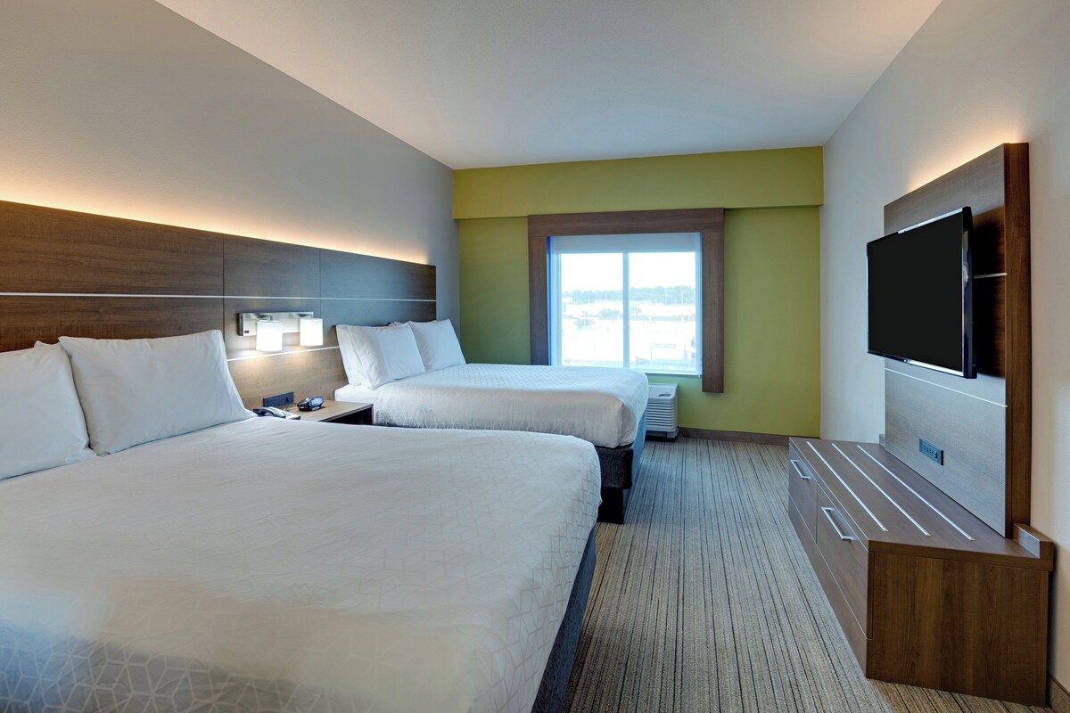 Habitación de hotel con dos camas, televisión, escritorio y ventana con vistas.