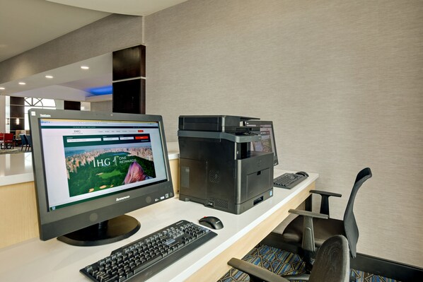 A hotel reception desk with a desktop computer, a printer, and a keyboard.