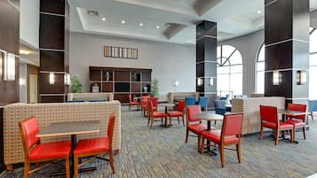Un vestíbulo moderno de hotel con zonas de estar, un mostrador de recepción y un gran ventanal que proporciona luz natural.