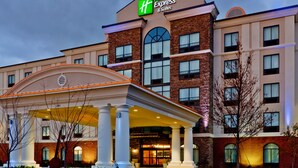 A Holiday Inn Express & Suites building with a covered entrance, multiple windows, and a brick facade. - Holiday Inn Express Hotel and Suites Nashville-Opryland by IHG (Nashville)