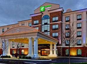 A Holiday Inn Express & Suites building with a covered entrance, multiple windows, and a brick facade.