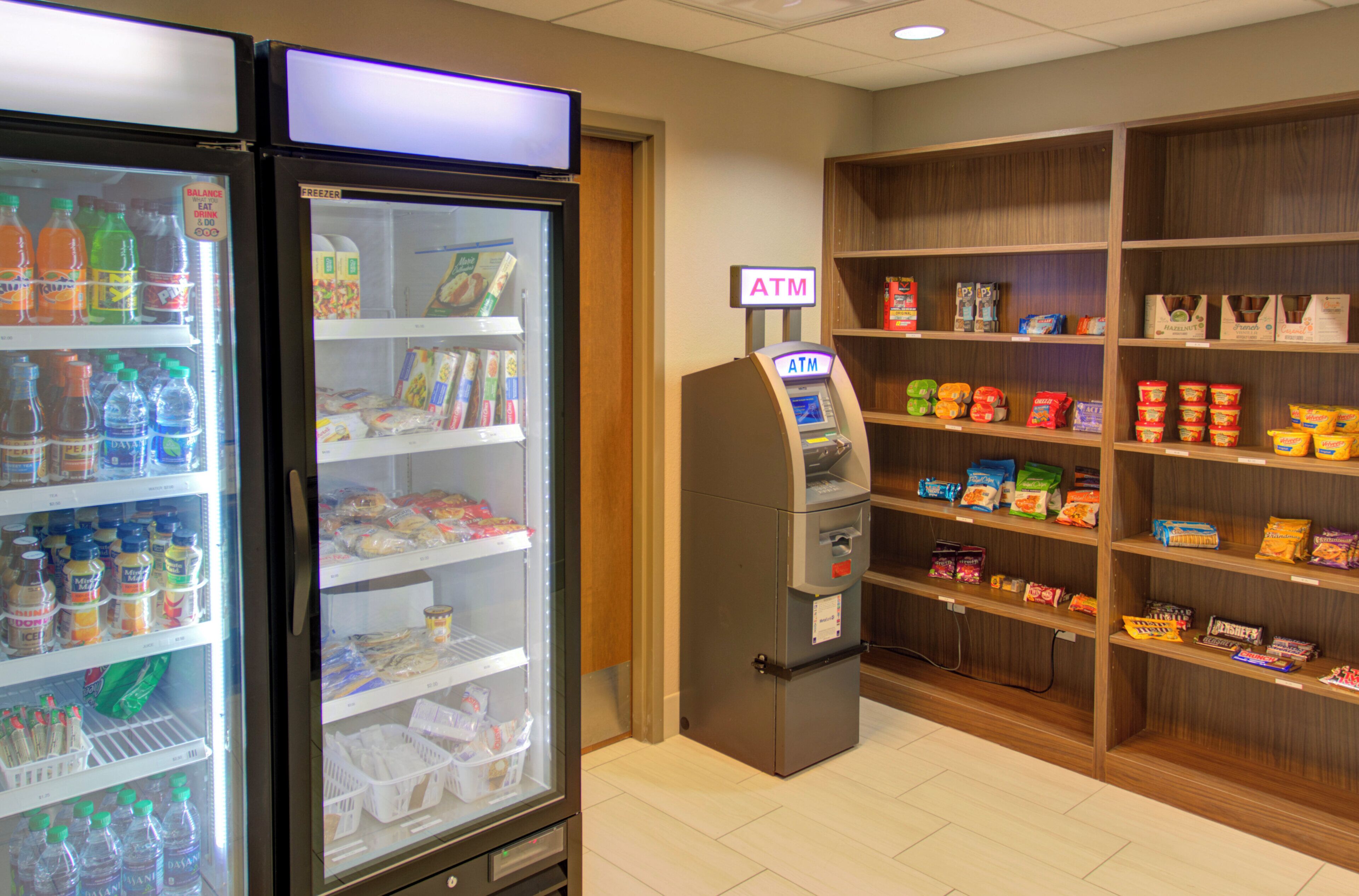 A self-service kiosk area with a freezer and shelves stocked with snacks and beverages.