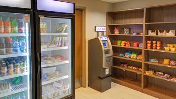 A self-service kiosk area with a freezer and shelves stocked with snacks and beverages.