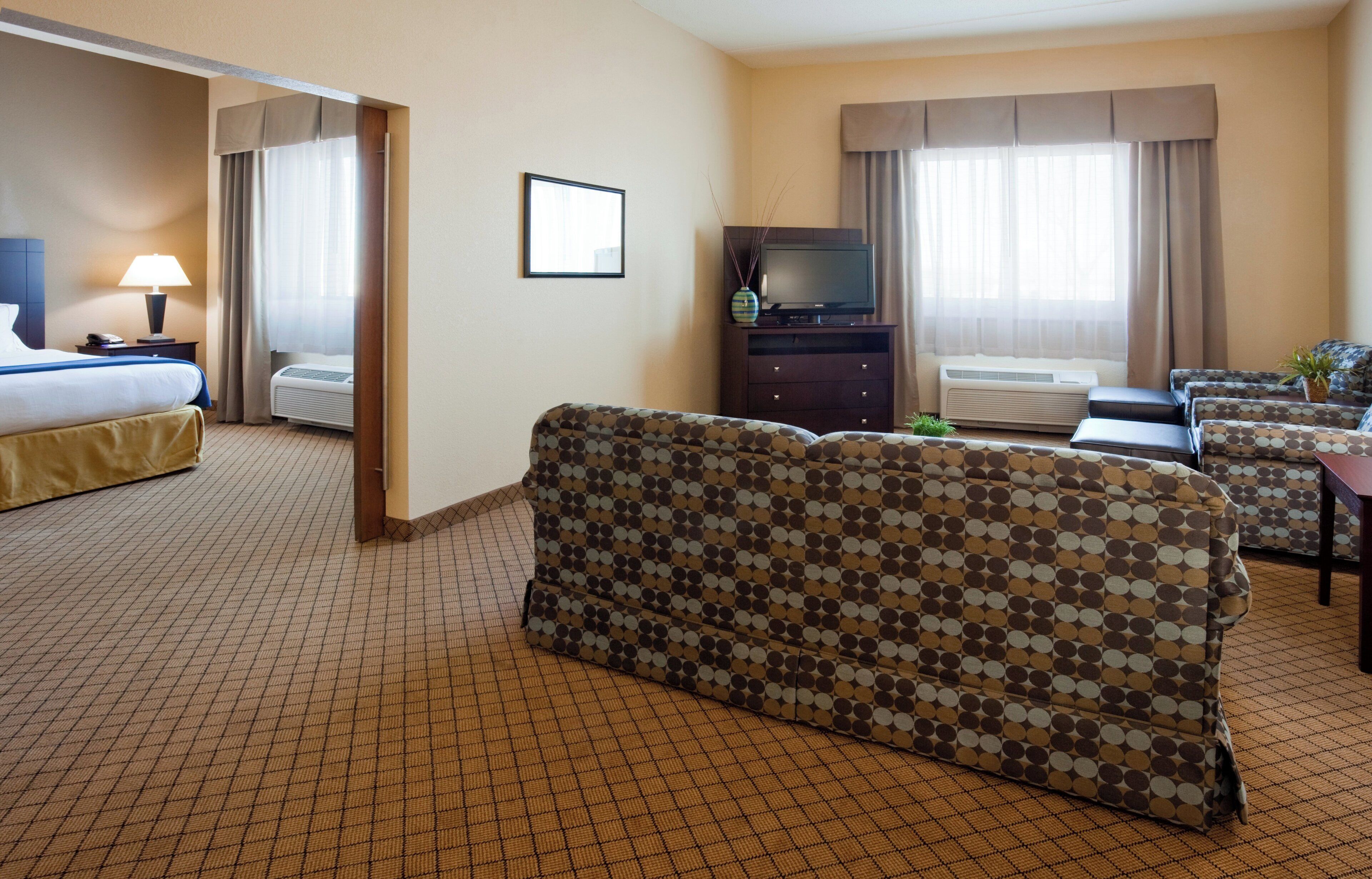 A hotel room with a bed, a sofa, a TV, and a desk.
