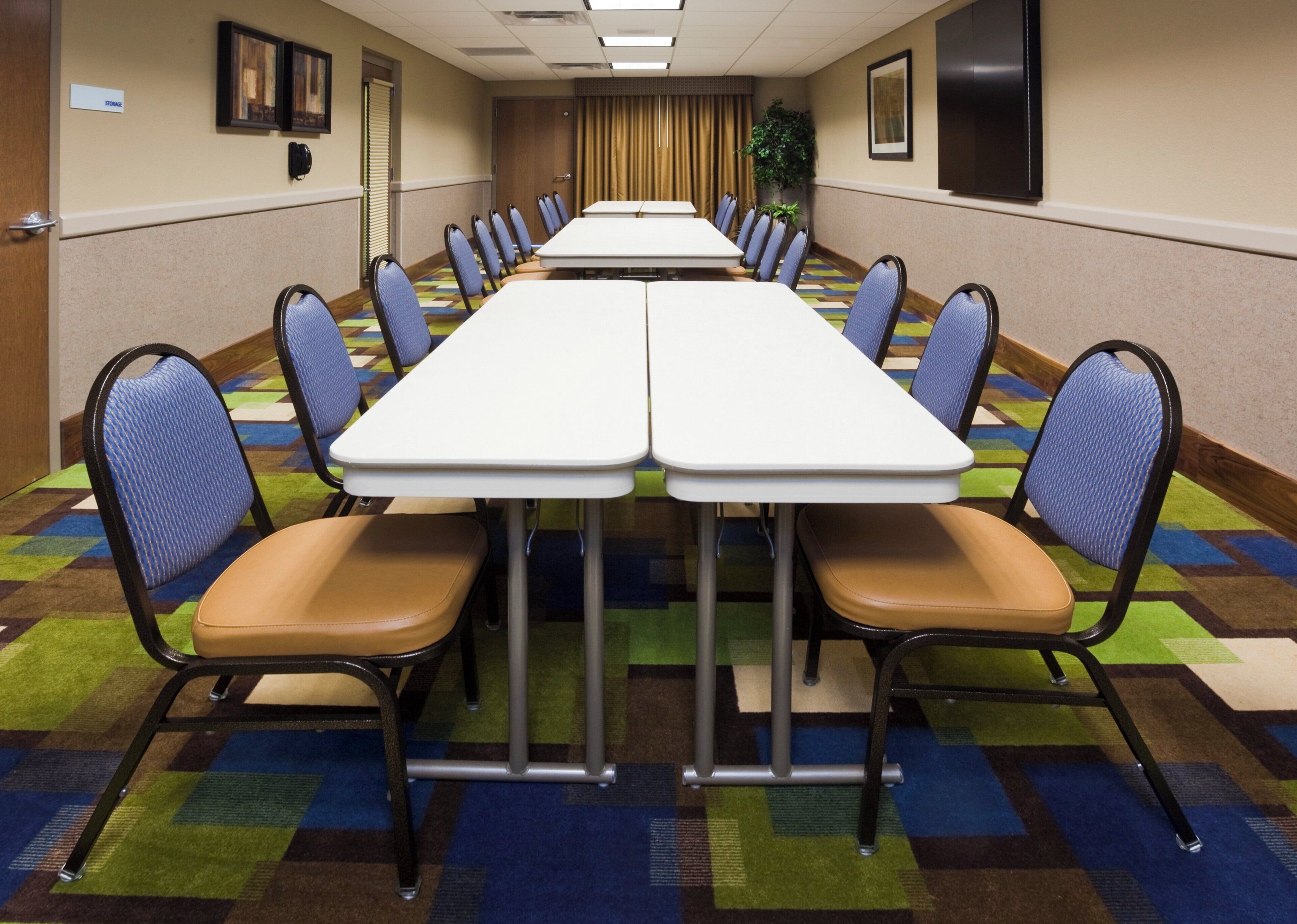 Une salle de conférence avec une longue table, des chaises et un tapis à motifs.