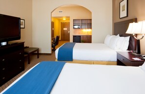 Ein Hotelzimmer mit zwei Betten, einem Schreibtisch, einem Fernseher und einer Küchenzeile.