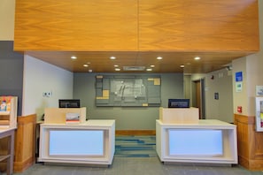 A reception area with two reception desks, a wall-mounted information board, and a ceiling with recessed lighting. - Holiday Inn Express Hotel and Suites Mankato East by IHG (Mankato)
