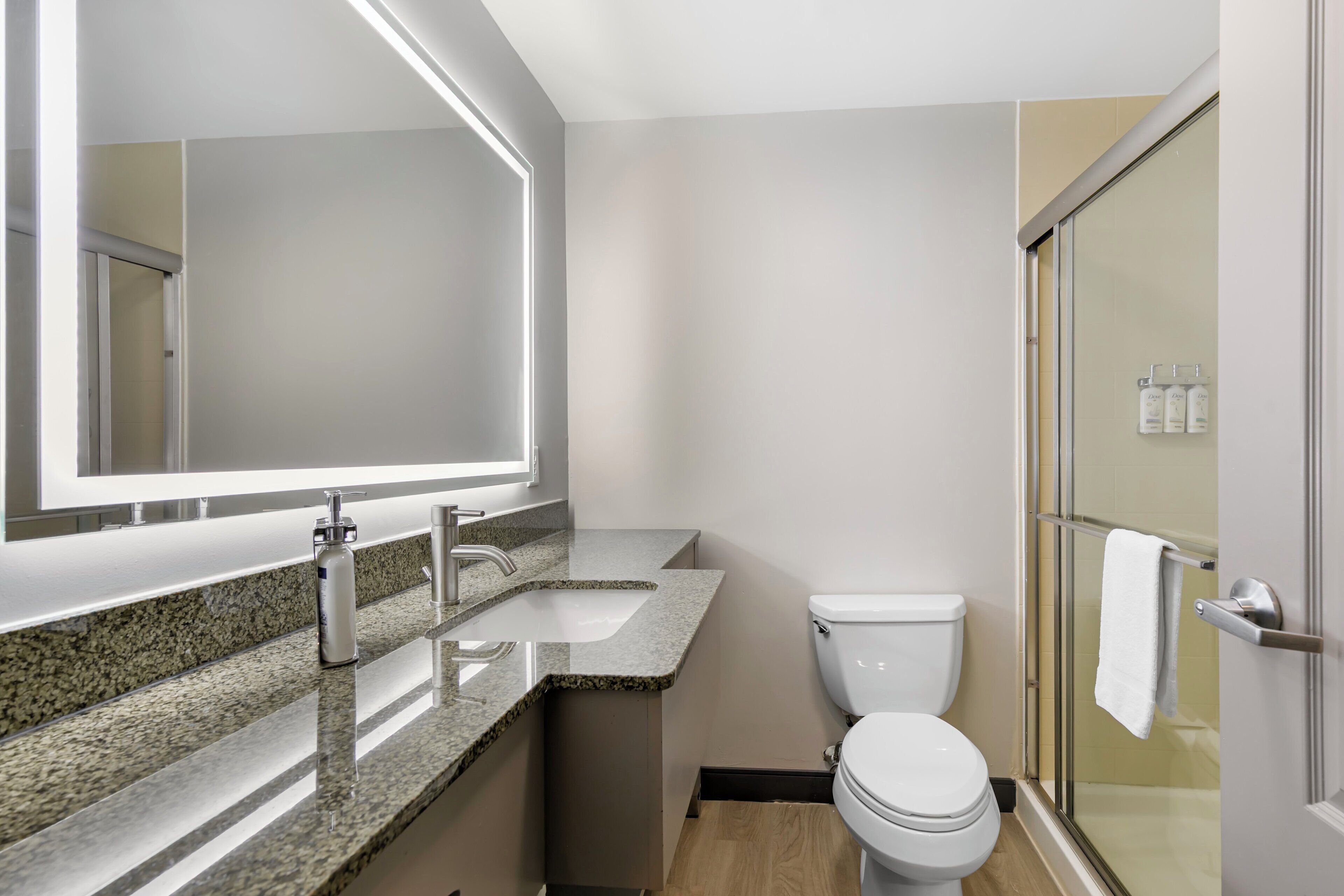 A modern bathroom with a large mirror, a sink, a toilet, and a shower area.