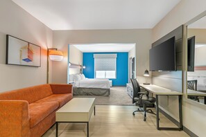 A hotel room with a bed, a desk, a chair, a sofa, a TV, and a window. - Holiday Inn Express & Suites Clemson by IHG (Clemson)