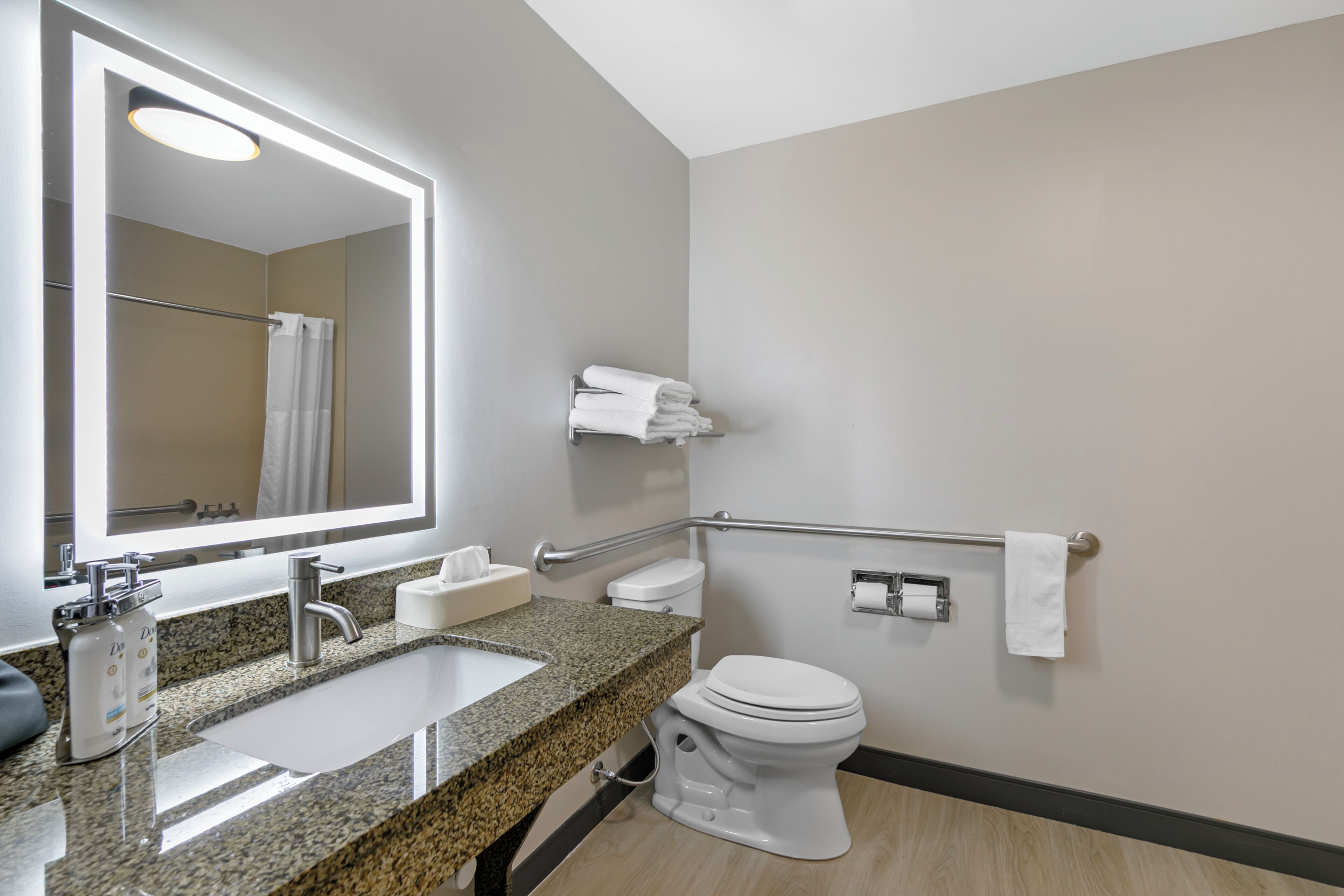 A bathroom with a sink, mirror, toilet, and towel rack.