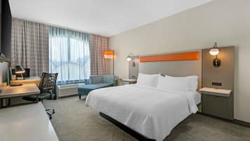 Een hotelkamer met een bed, bureau, stoel en twee wandlampen.