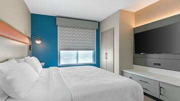 A modern hotel room with a large bed, a flat-screen TV, a desk, and a window with a view.