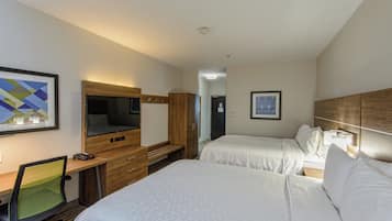 A hotel room with two beds, a desk with a chair, a television, and a wardrobe.