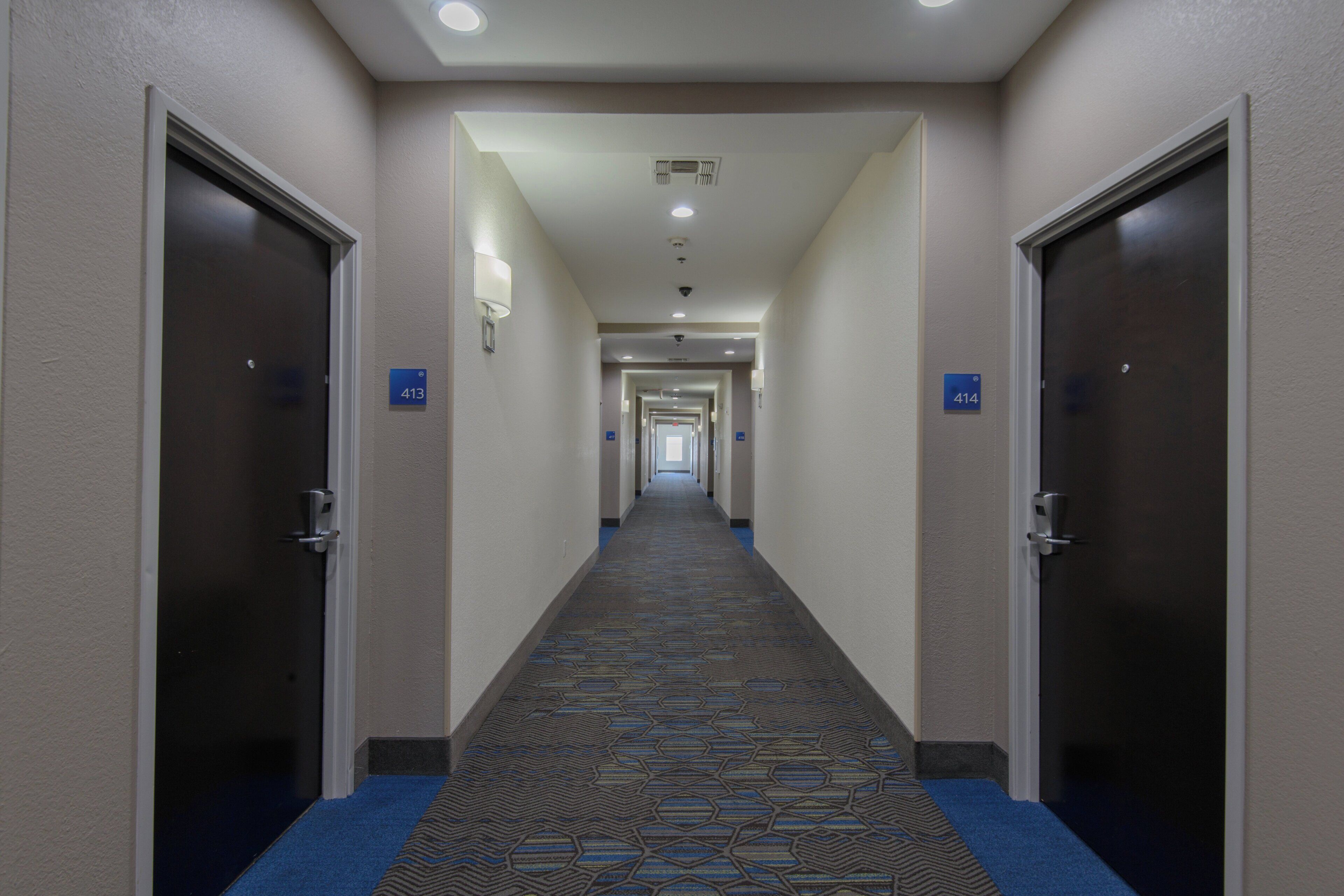 Un couloir d’hôtel avec des portes numérotées 413 et 414, donnant accès aux chambres.