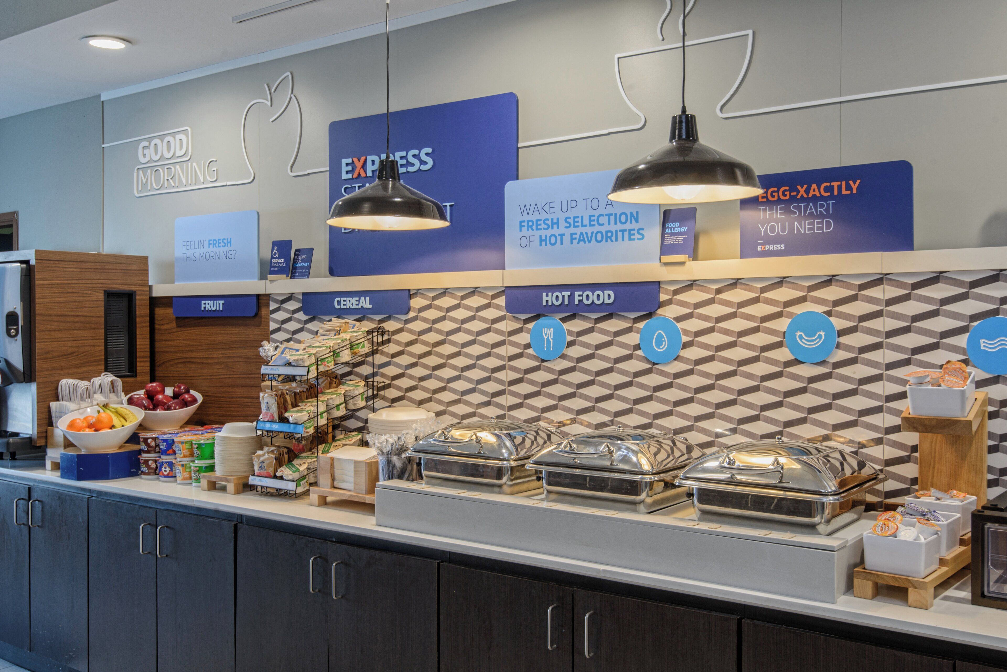 A breakfast buffet with labeled sections for fruit, cereal, and hot food.