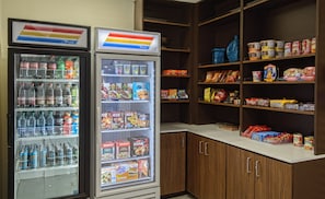 A vending machine stocked with various beverages and snacks, and a shelf with packaged food items.