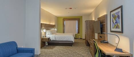 A hotel room with a bed, a desk, a chair, a sofa, and a television.