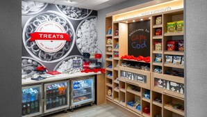 Een kiosk voor snacks en drankjes, met een bord waarop 'Treats' staat, een krijtbordmenu en planken vol met verschillende snacks en drankjes.