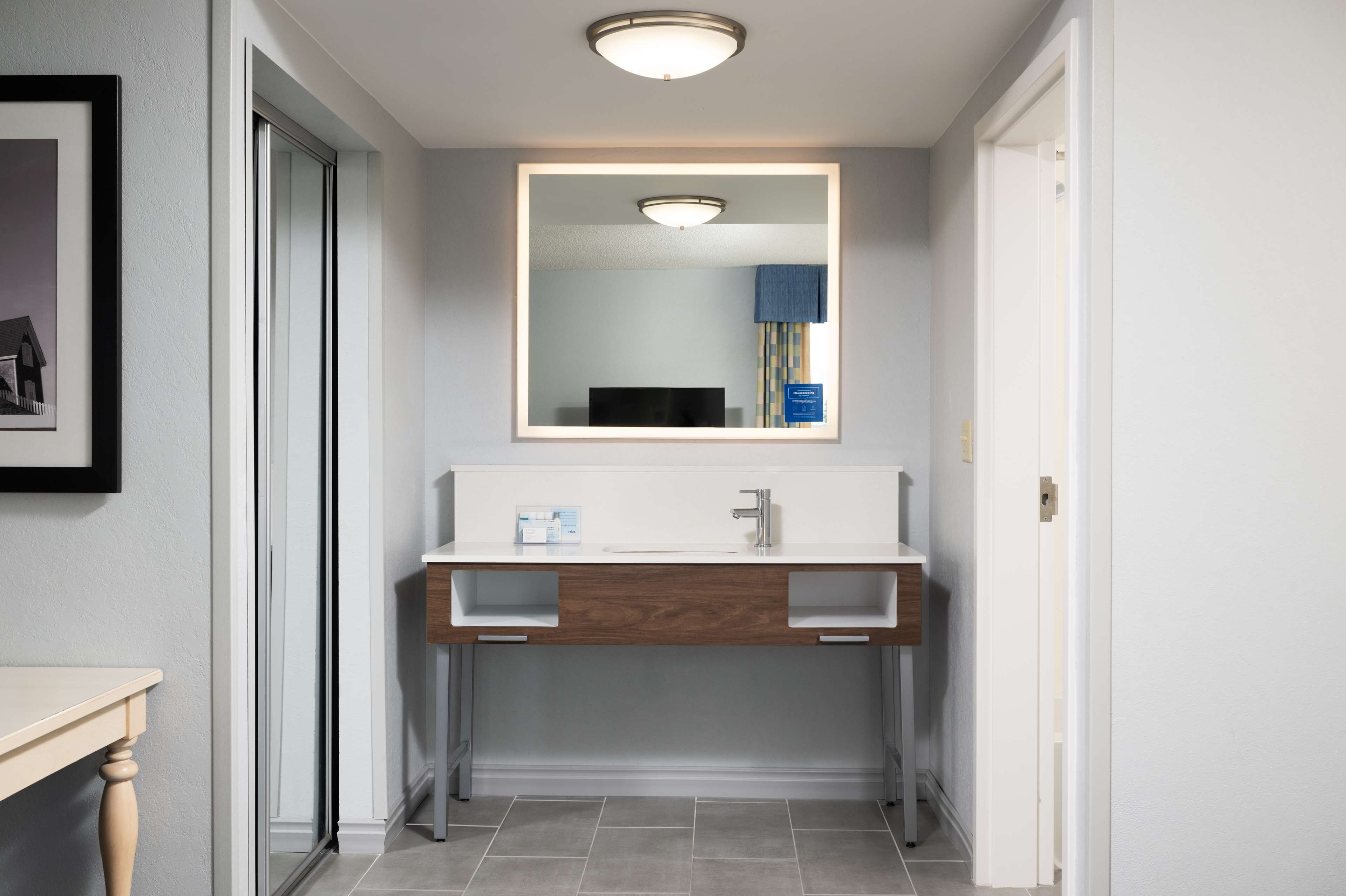 A modern bathroom with a white vanity, a large mirror, and a recessed ceiling light.