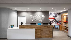 Een receptiegedeelte met een bord waarop 'Welcome to the Patriot State' staat en een balie met een 'Hilton'-bord.