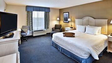 A hotel room with a large bed, a television, a desk, and a chair.