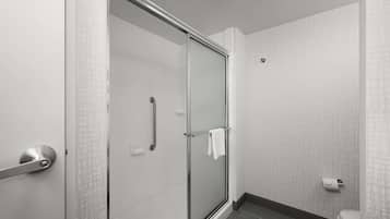 Une salle de bain moderne avec une douche à parois de verre, des toilettes blanches et un sol carrelé.