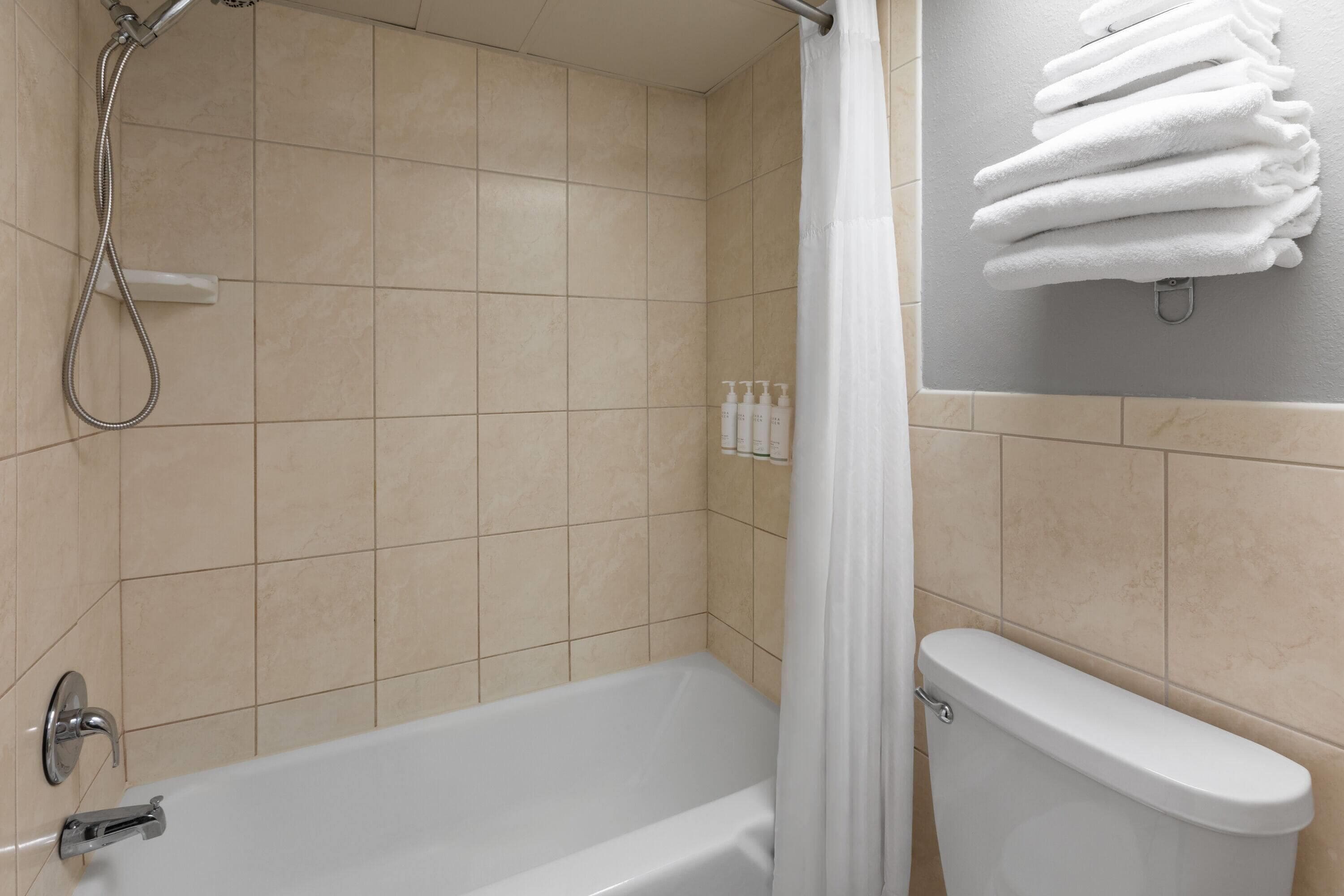 A bathroom with a bathtub, shower, and toilet.