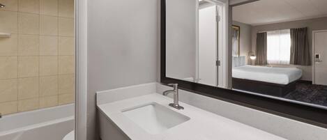 A modern bathroom with a white sink, a large mirror, and a visible shower area.