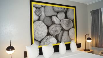 A hotel room with a bed, bedside lamps, a large framed rock artwork, and a curtain.