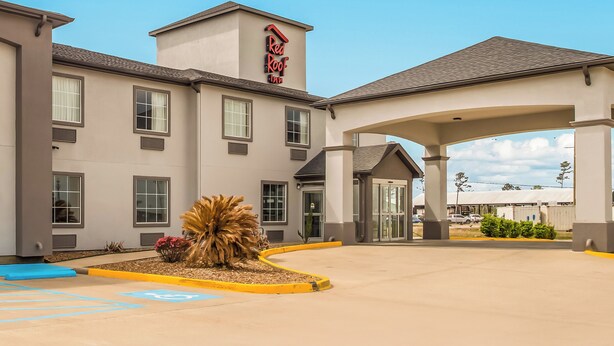 Entrada de hotel con un corredor cubierto, un letrero de Red Roof Inn y un área de estacionamiento con acceso para discapacitados.
