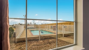 Vista de una piscina con zona vallada, terraza de madera y cielo despejado.