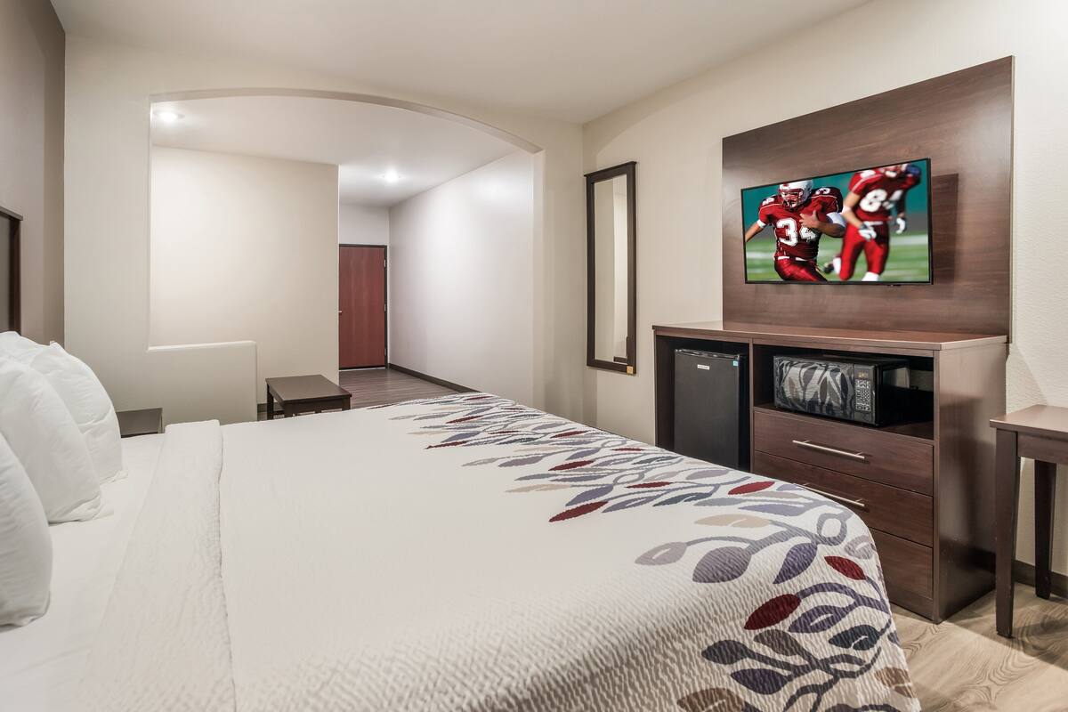 Hotelkamer met een groot bed, een flatscreen televisie aan de muur, een houten dressoir en een magnetron.