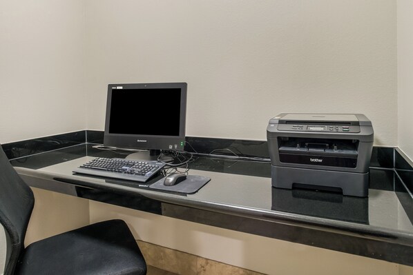 A desktop computer with a monitor, keyboard, mouse, and printer on a black and white tiled desk.