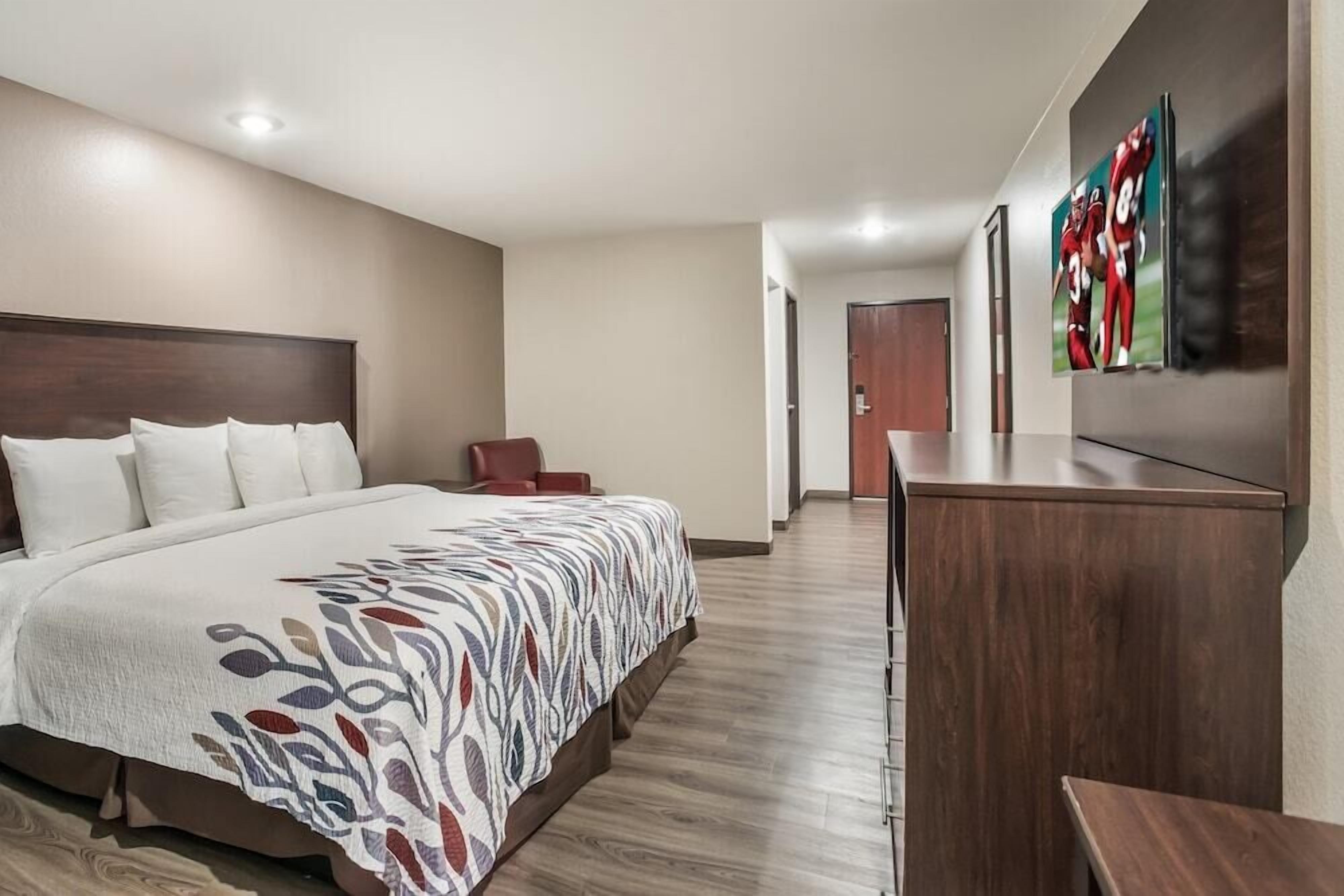 Een hotelkamer met een groot bed, een bureau en een deur die naar een andere kamer leidt.